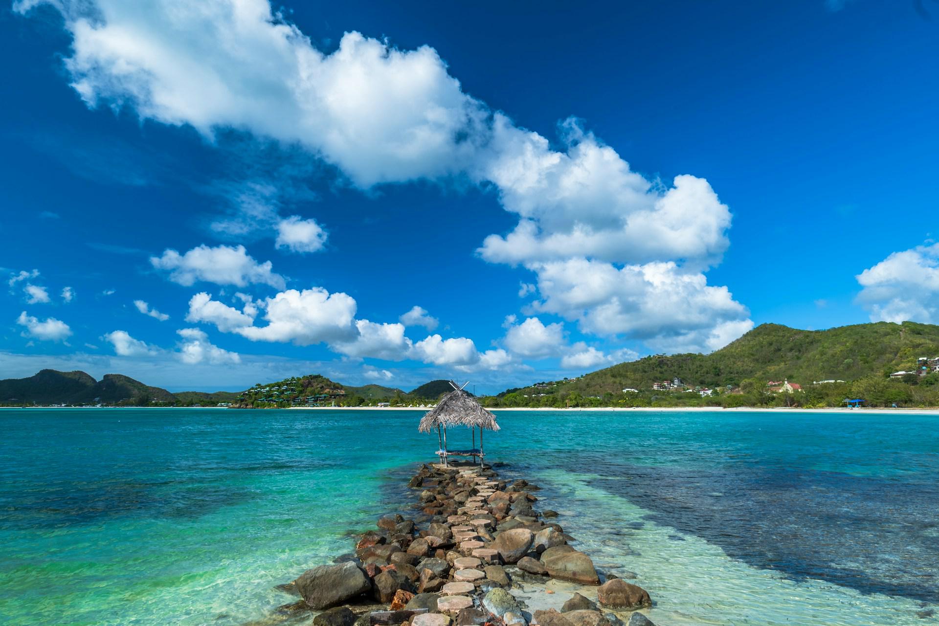 Turquoise water and a thatched shelter on a rocky jetty in Antigua and Barbuda