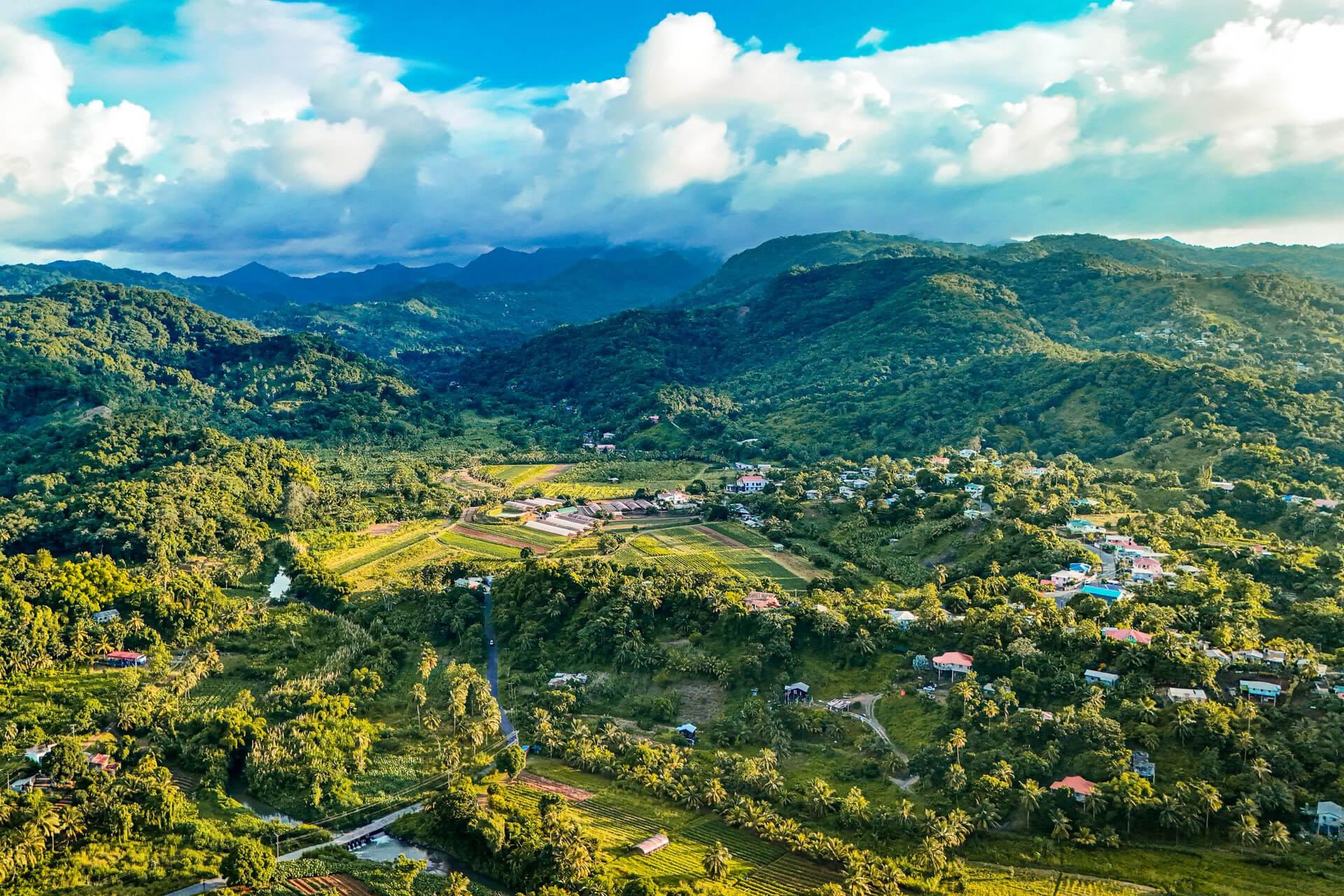 A breathtaking aerial shot over lush Caribbean mountains and valleys under a vibrant blue sky, Saint Lucia