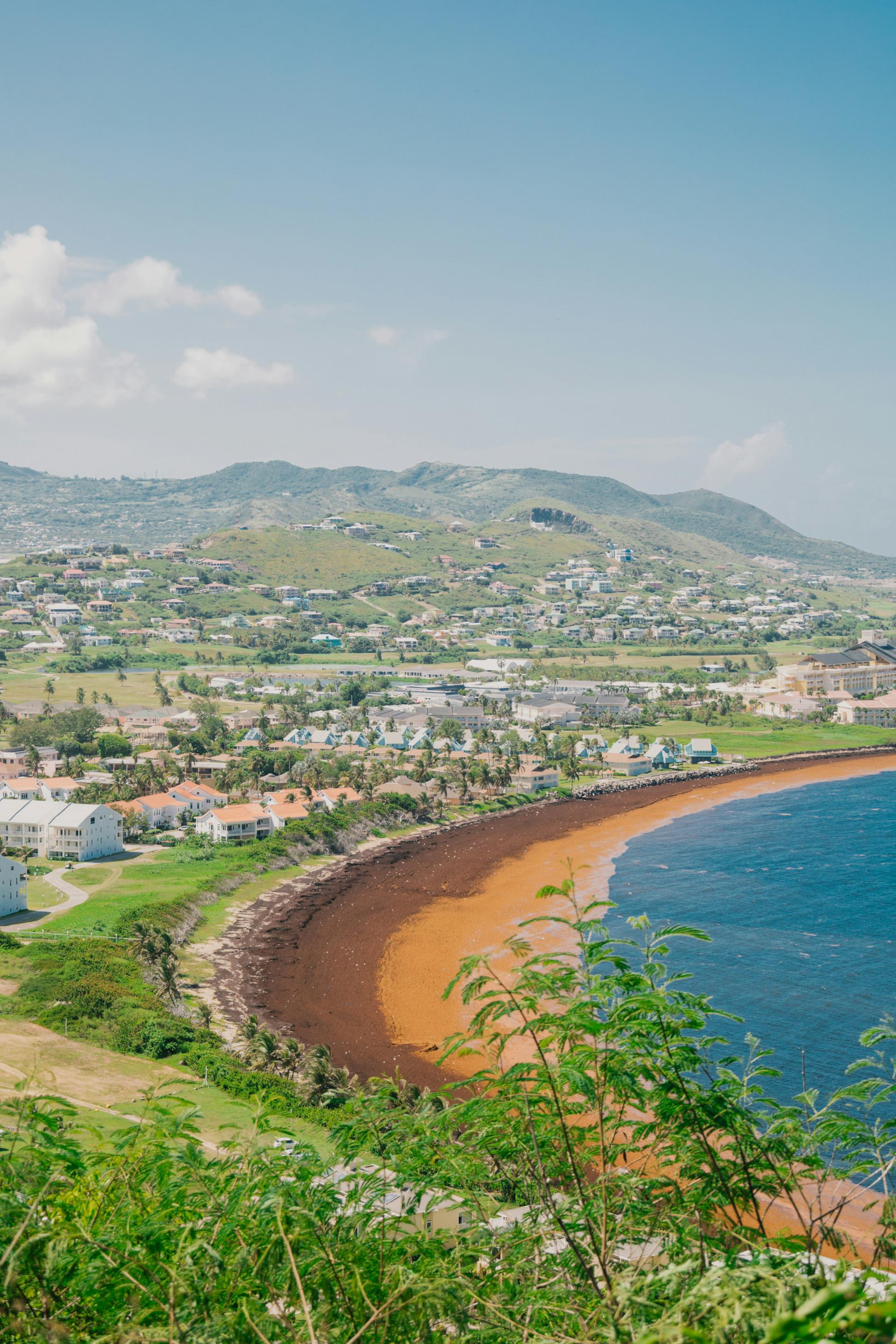 Frigate Bay beach and coastal homes beneath green hills on St Kitts