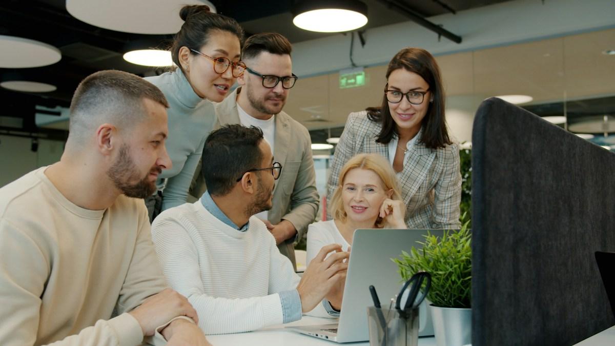 Colleagues talking over a laptop in a meeting room