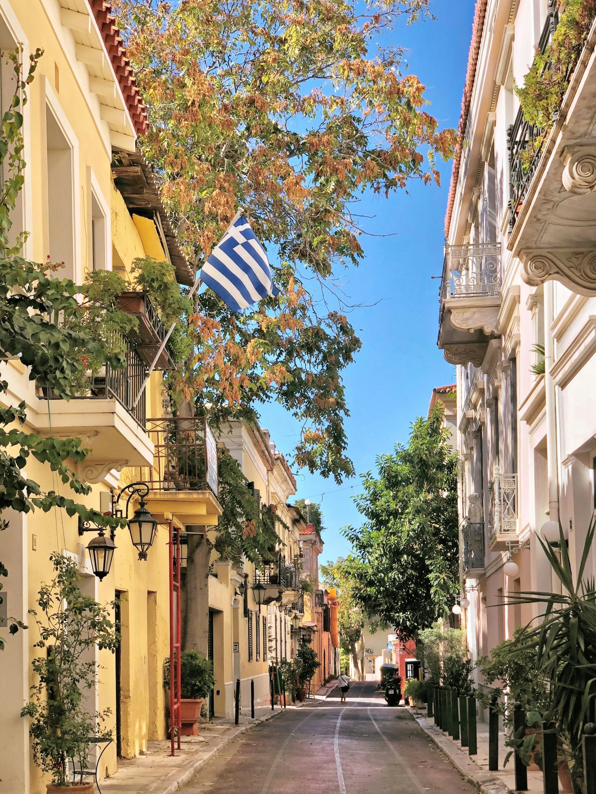 Residential buildings, balconies and a Greek flag on a street in Plaka, Athens, Greece