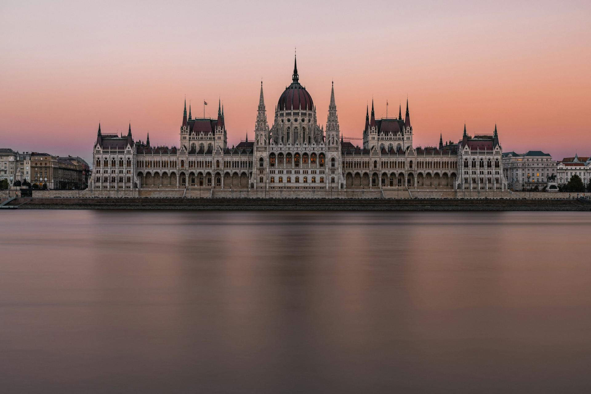 The Hungarian Parliament and Danube River beneath a pink evening sky in Budapest