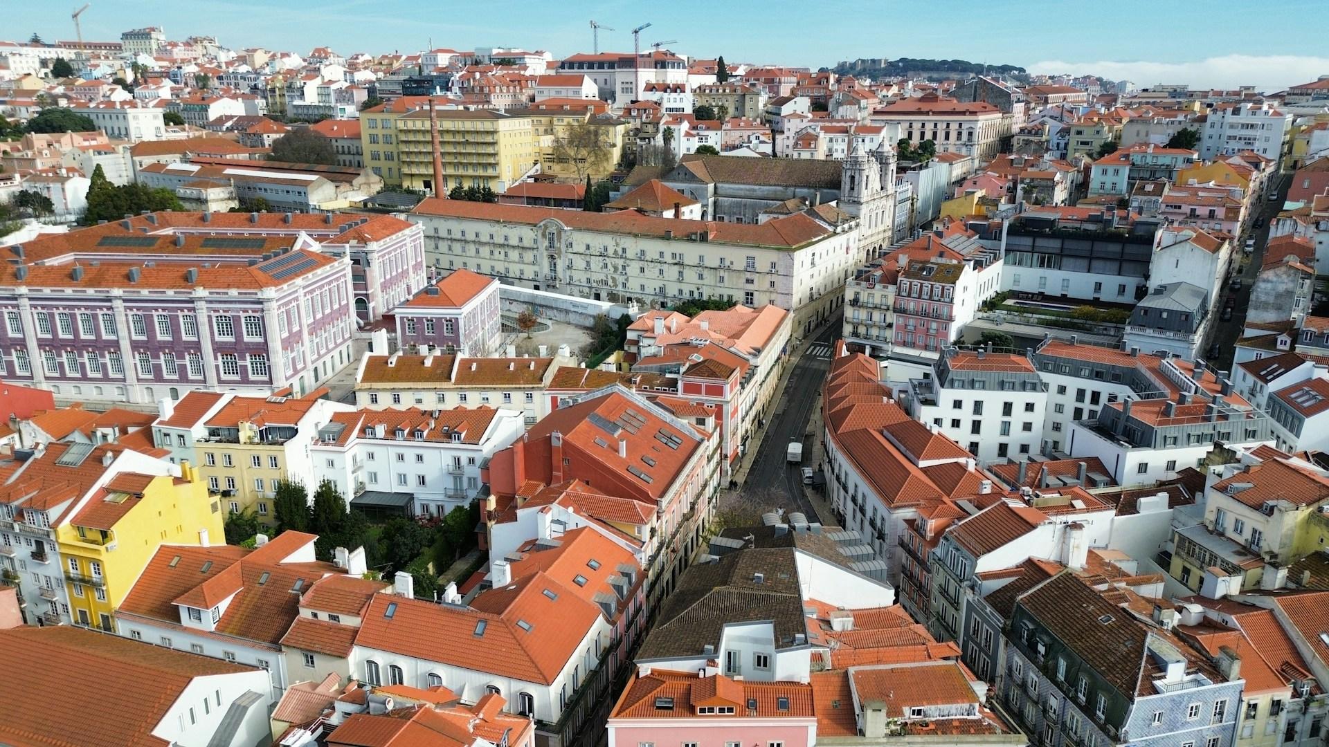 Aerial view of red-tiled rooftops, pastel buildings and a church in Lisbon, Portugal