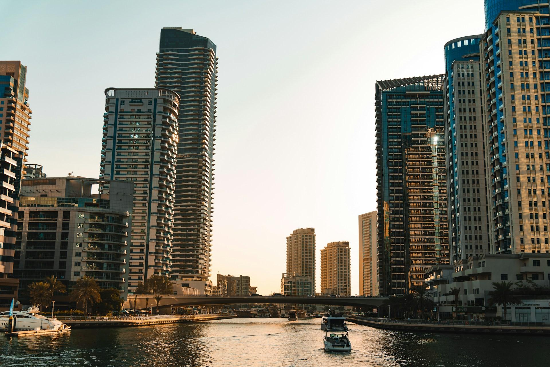 Dubai Marina waterfront with modern towers, boats and a bridge in the evening light