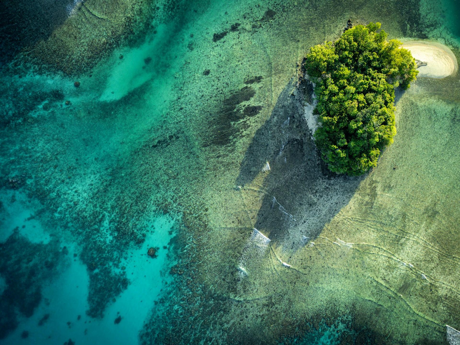Aerial view of a forested island and clear turquoise water near Espiritu Santo, Vanuatu